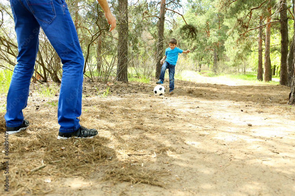 Fototapeta premium Happy dad and son playing football in the park