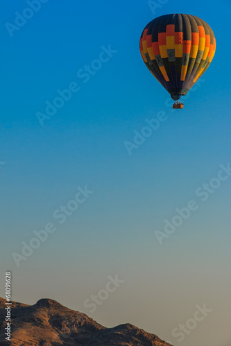 Hot air balloon floating above mountain