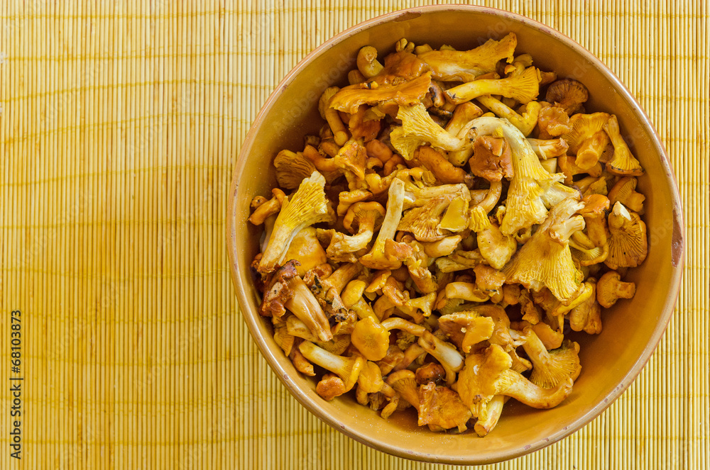 chanterelle mushrooms in an old bowl on a bamboo mat