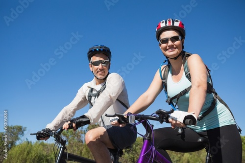 Fototapeta Naklejka Na Ścianę i Meble -  Active happy couple going for a bike ride in the countryside