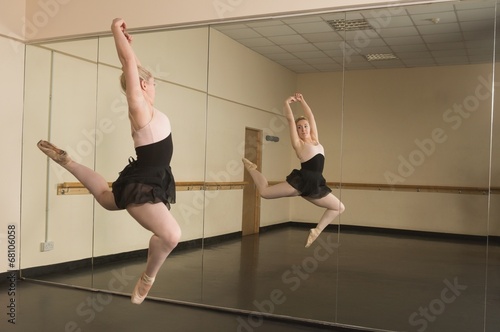 Beautiful ballerina dancing in front of mirror