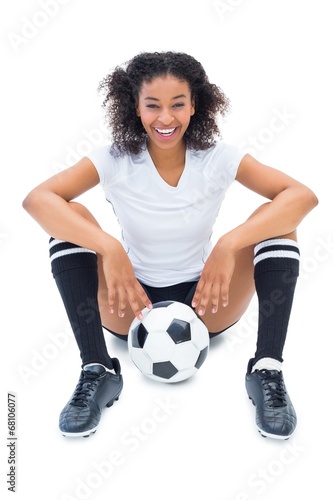 Pretty football player in white sitting on floor with ball