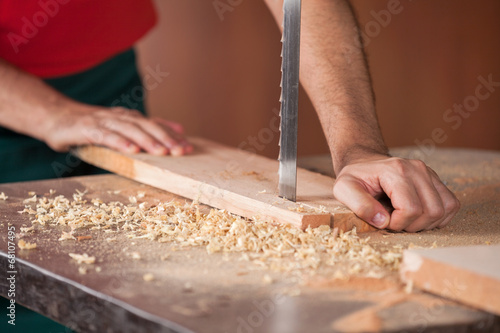 Carpenter's Hands Cutting Wood With Bandsaw photo