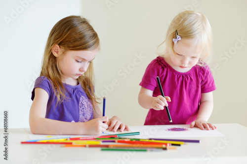 Two little sisters drawing with colorful pencils