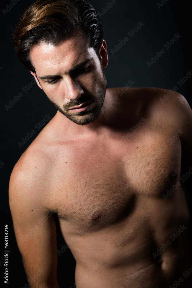 Handsome muscular male model posing over black background. Handsome muscular male model posing over black background.