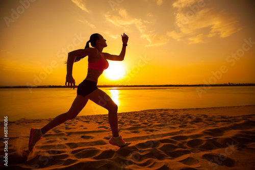 Woman running alone at beautiful sunset in the beach. Summer spo