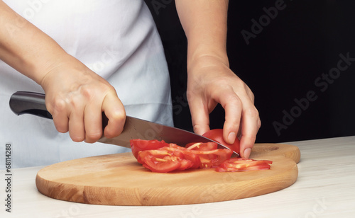 Female hands cutting tomato