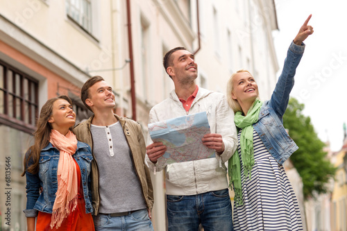 group of smiling friends with map exploring city