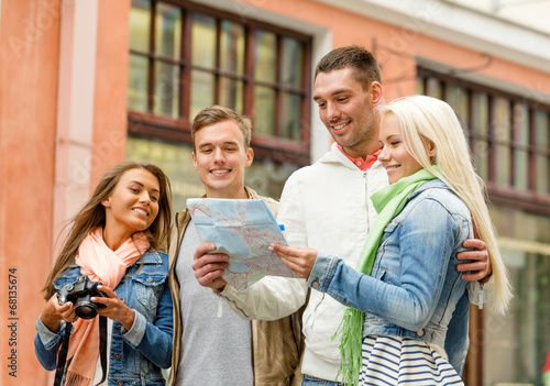 group of smiling friends with map and photocamera