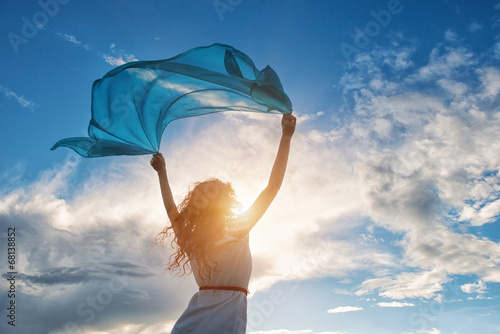 Obraz na płótnie Beautiful young woman holding blue scarf on the wind