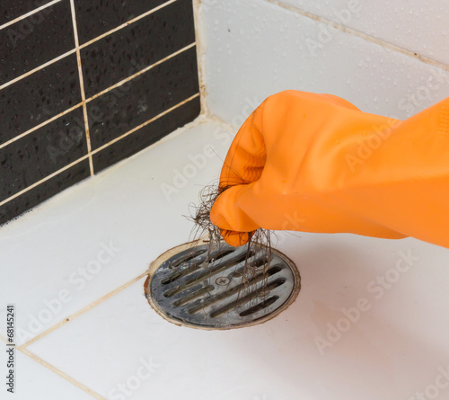 Cleaning bathroom  hair clogged with orange gloves.