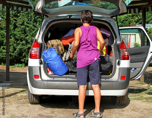 boy loads his bags in the car after the holidays