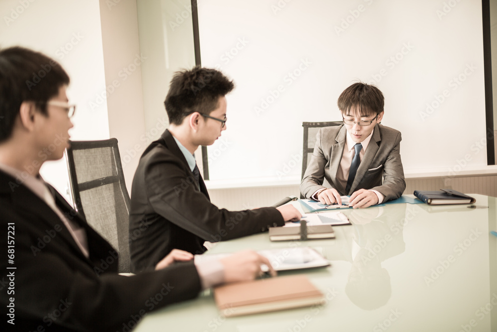 Young business people sitting in board room during meeting and d Young business people sitting in board room during meeting and d