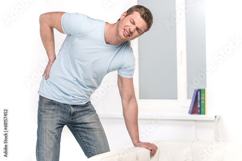 Handsome man leaning on sofa and feeling pain.