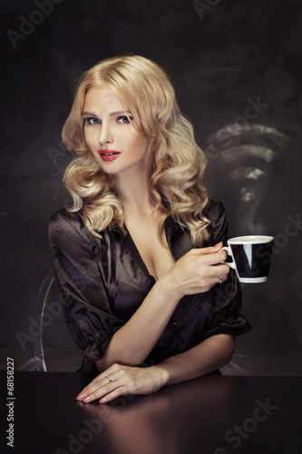 Beautiful woman holding the vaporous cup of coffee