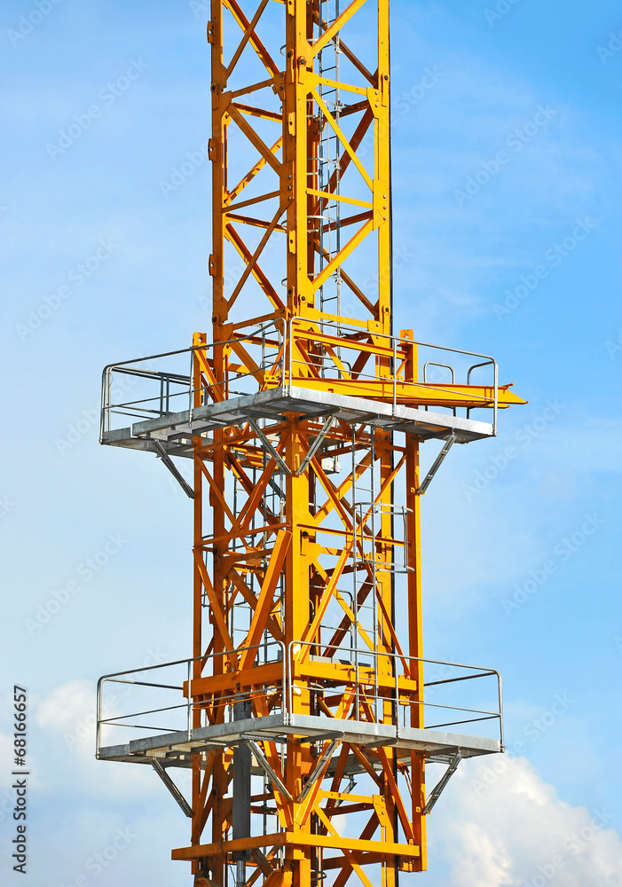 Yellow construction tower crane against blue sky