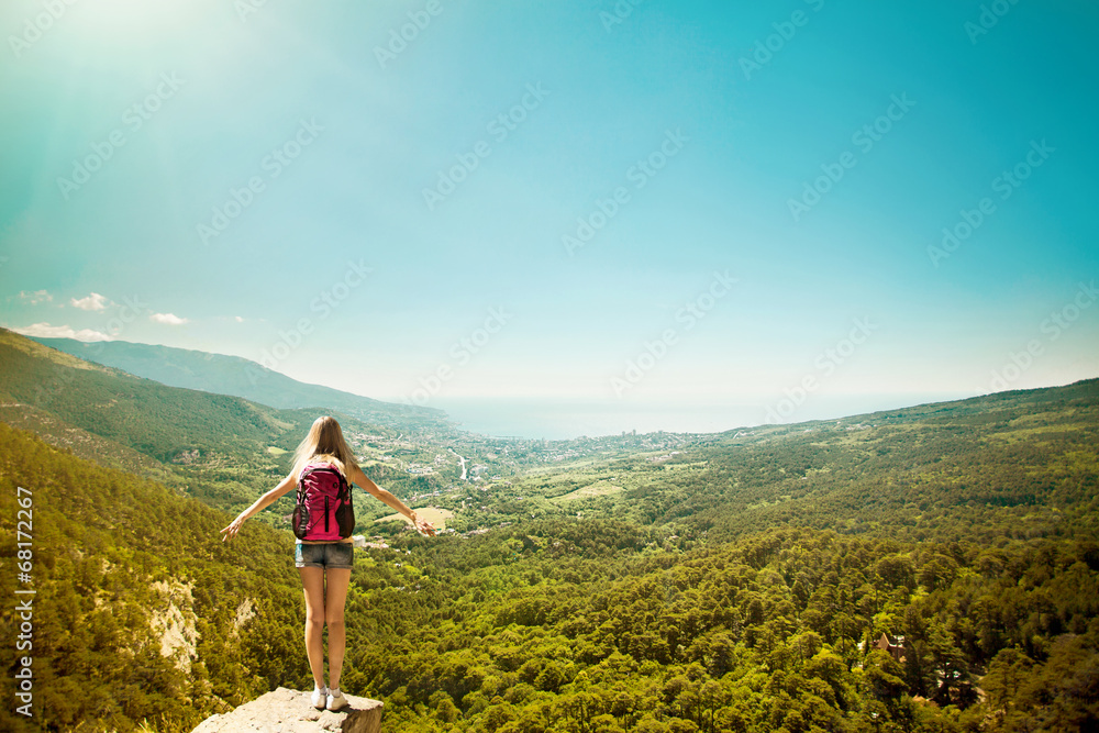 Fototapeta premium Young woman with backpack standing on cliff edge
