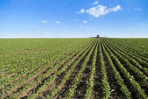 Tractor spraying soybean crop field