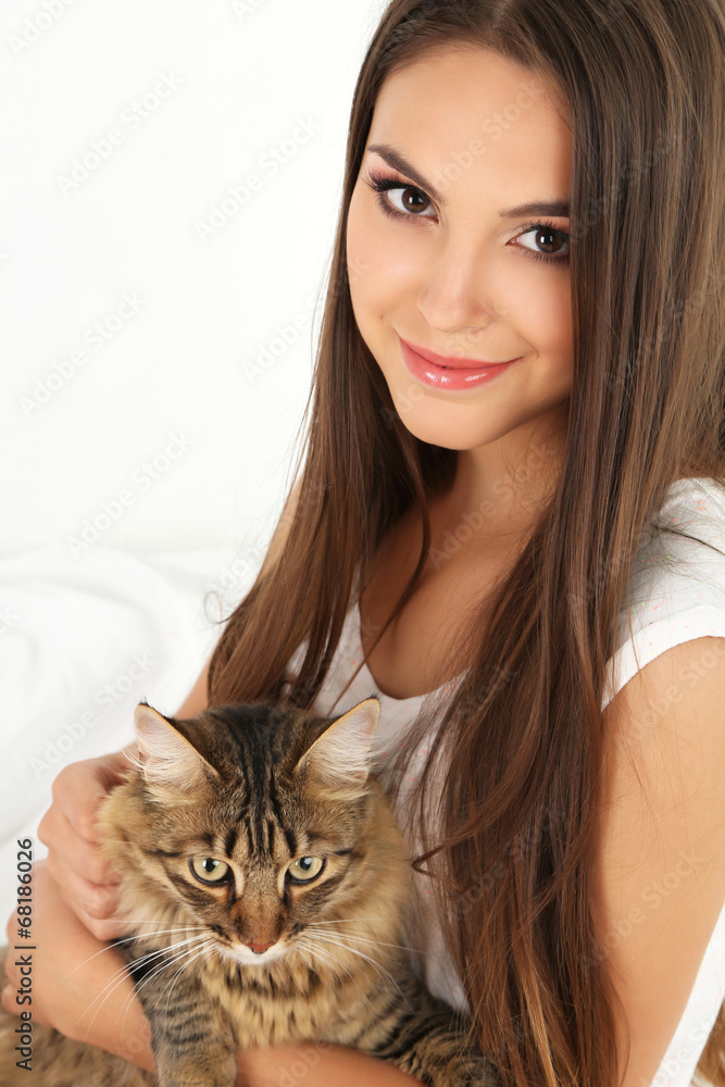 Beautiful young woman with cat sitting on bed Beautiful young woman with cat sitting on bed