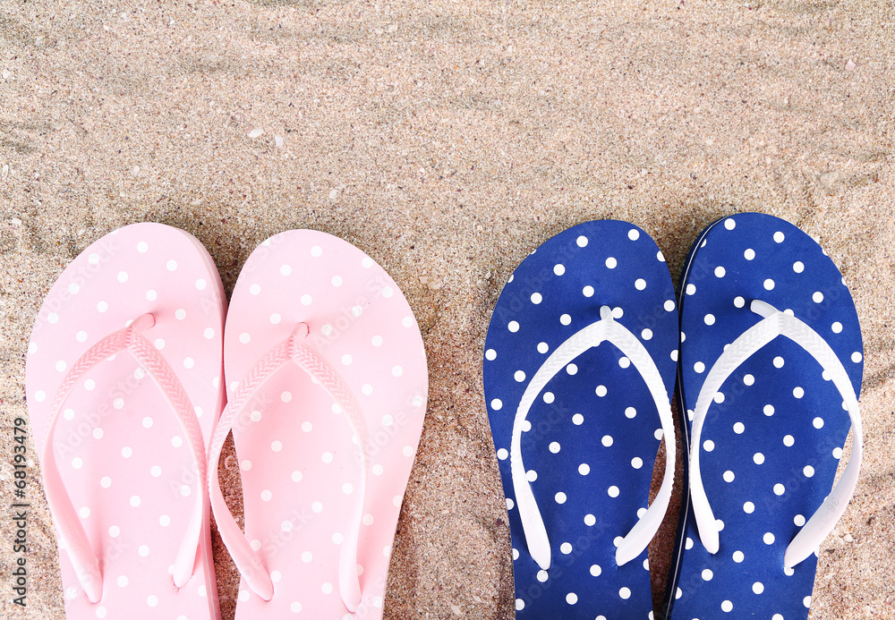 Fototapeta premium Color flip-flops on sand background