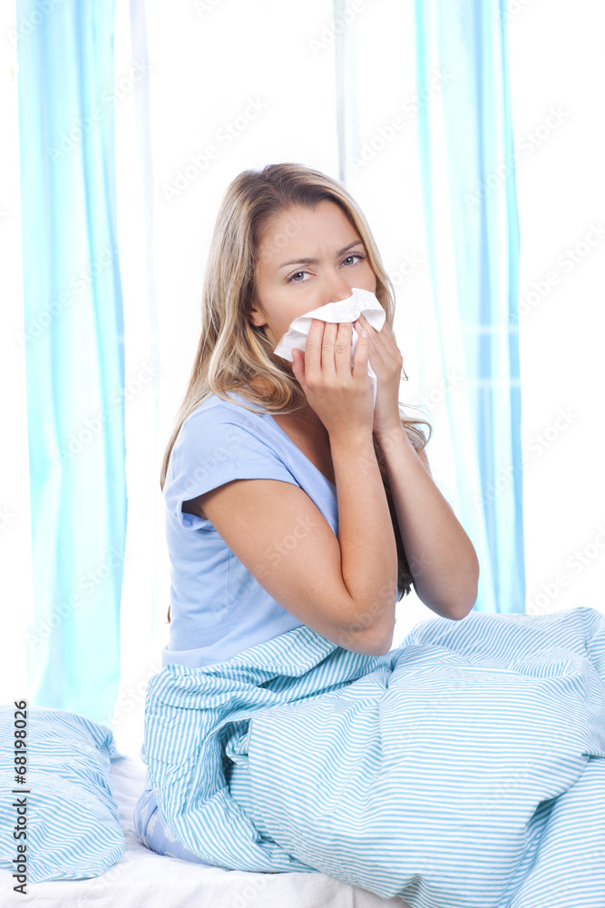 Junge Frau mit Taschentuch im Bett
