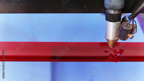 Laser cnc machine cutting technology word on red acryl plate