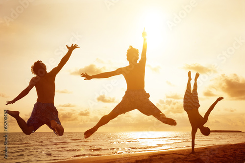 young people jumping on the beach with sunset background