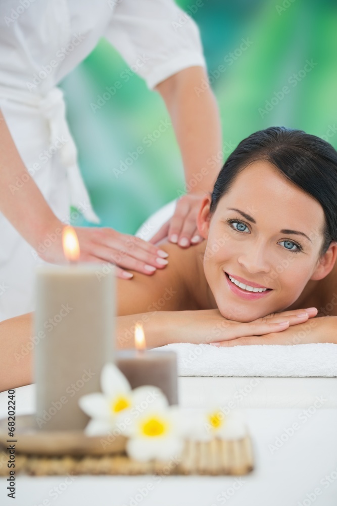 Beautiful brunette enjoying a back massage smiling at camera Beautiful brunette enjoying a back massage smiling at camera