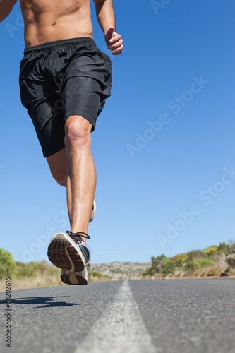 Shirtless man jogging on open road