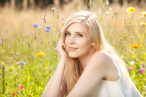 Hübsche blonde Frau vergnügt sich auf einer Blumenwiese