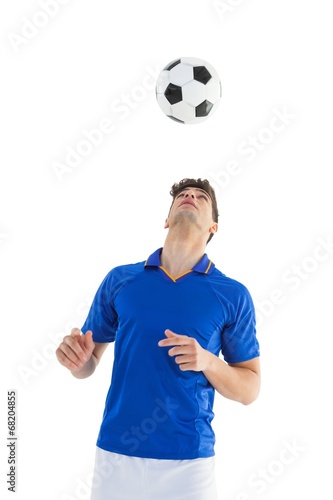 Football player in blue jersey heading ball