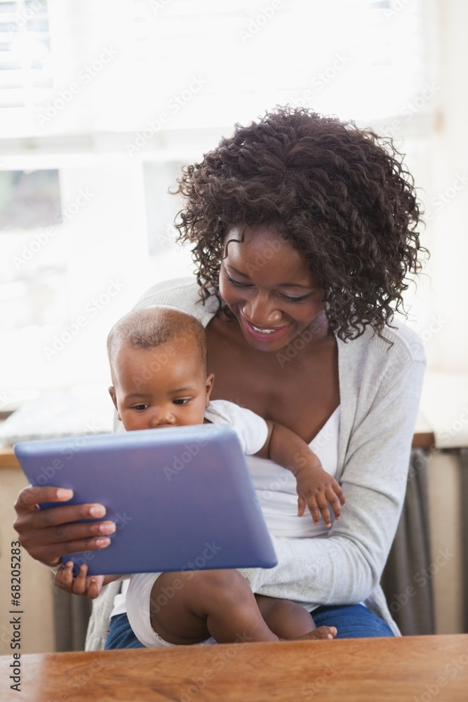 Happy mother holding baby son while using tablet pc Happy mother holding baby son while using tablet pc