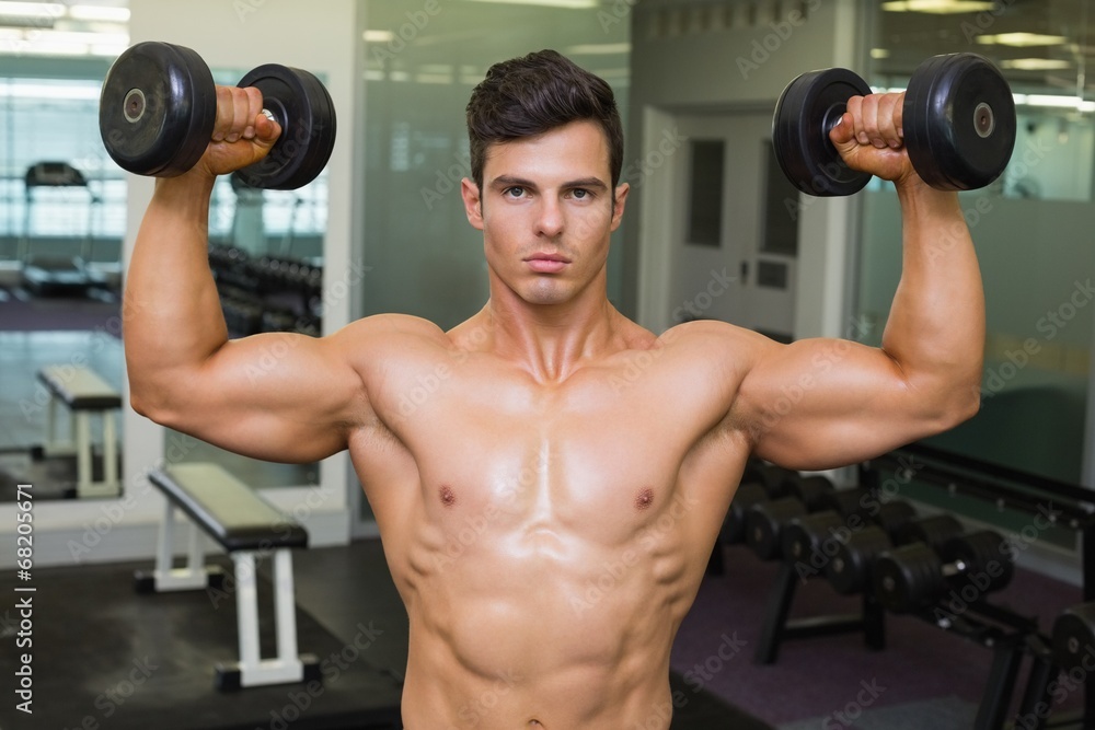 Shirtless muscular man exercising with dumbbells Shirtless muscular man exercising with dumbbells