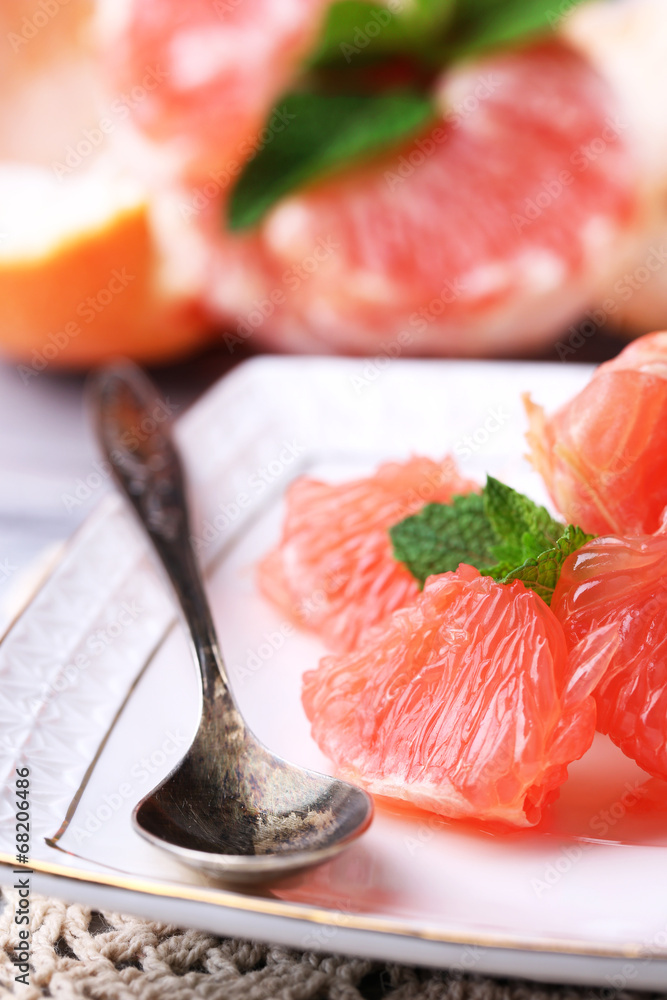 Ripe peeled grapefruits on plate, on color wooden background Ripe peeled grapefruits on plate, on color wooden background