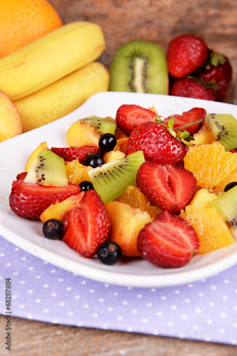 Fresh fruits salad on plate with on table close up