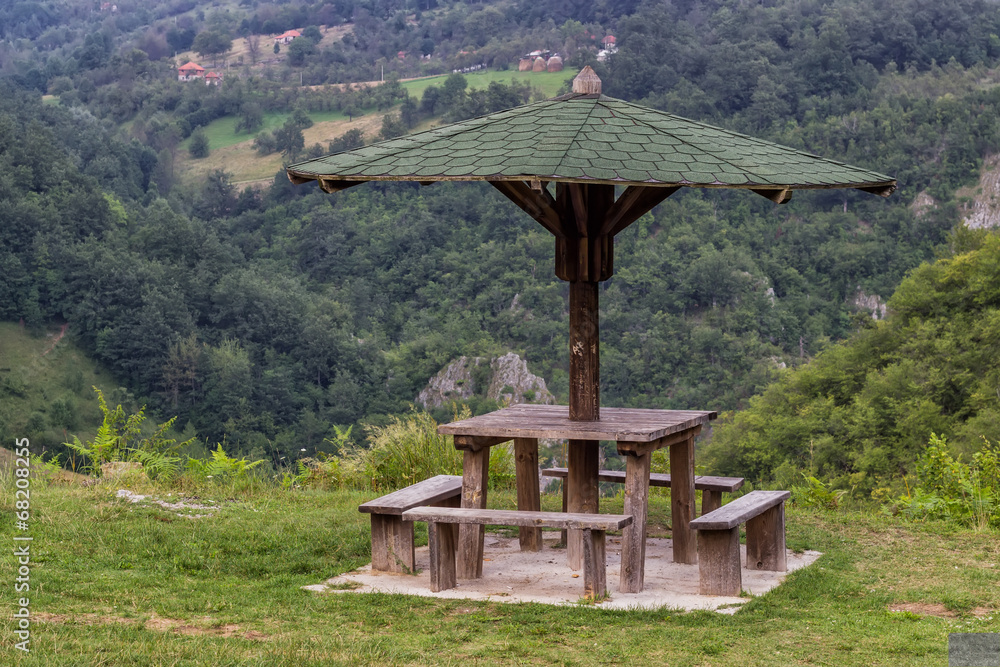Wooden seating bench with table in nature under wooden umbrella