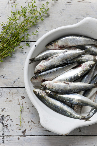 sardines on enamelled tray with thyme on rustic background