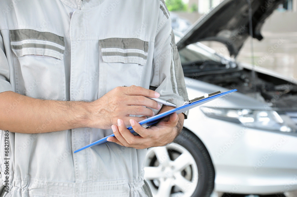 A mechanic holding clipboard in front of the car - car checking 