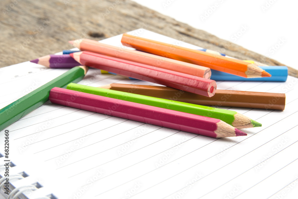 Blank paper and colorful pencils on the wooden table.