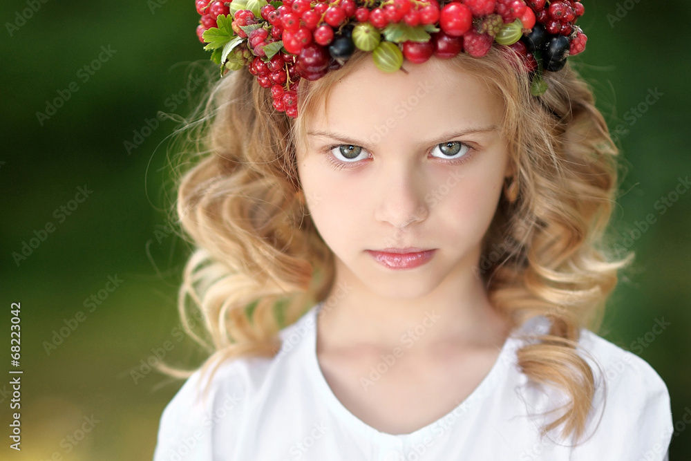 Naklejka premium portrait of a beautiful little girl with berries