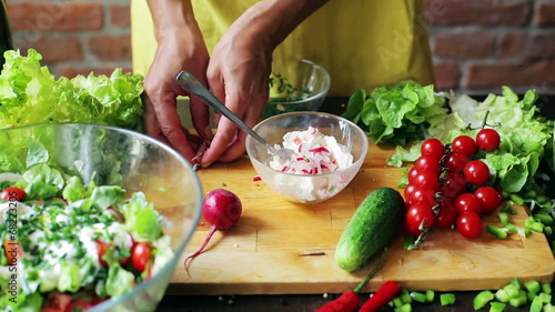 Woman adding radish and chives to the cheese, closeup