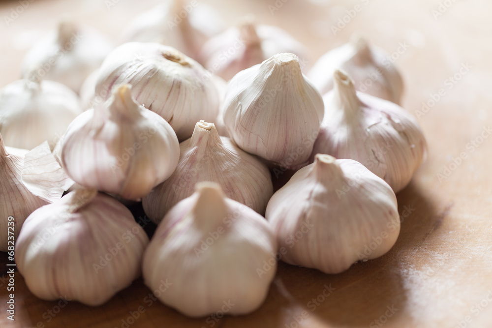 a clove of garlic and a whole wooden table closeup a clove of garlic and a whole wooden table closeup