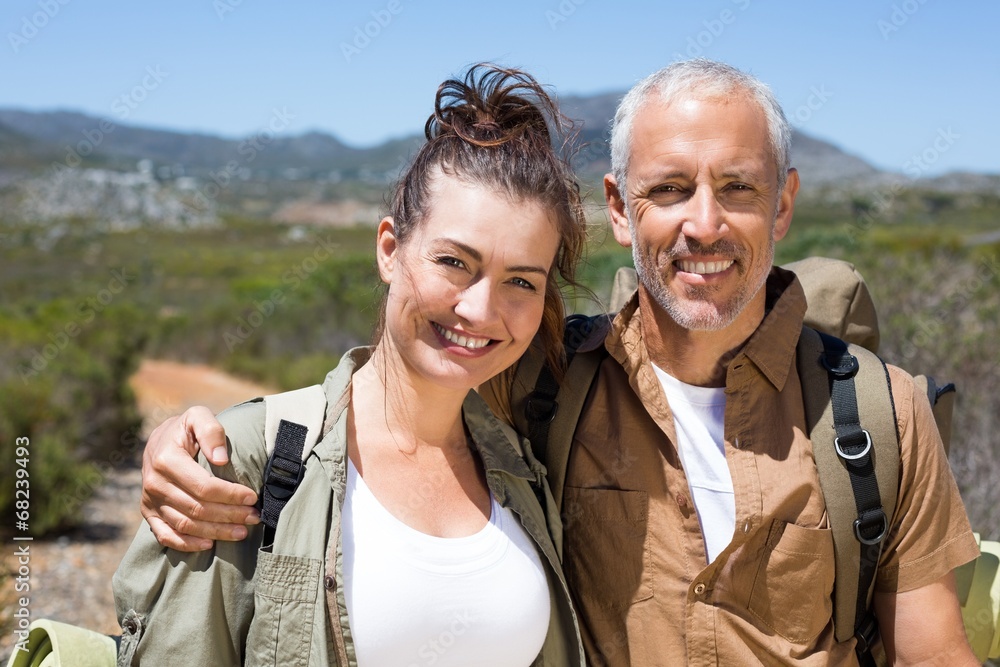 Naklejka premium Hiking couple smiling at camera on mountain trail