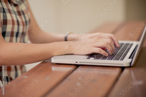 Woman using laptop indoor.close-up hand