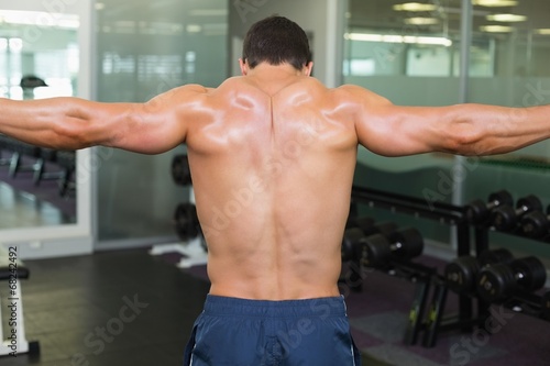 Bodybuilder with arms outstretched in gym