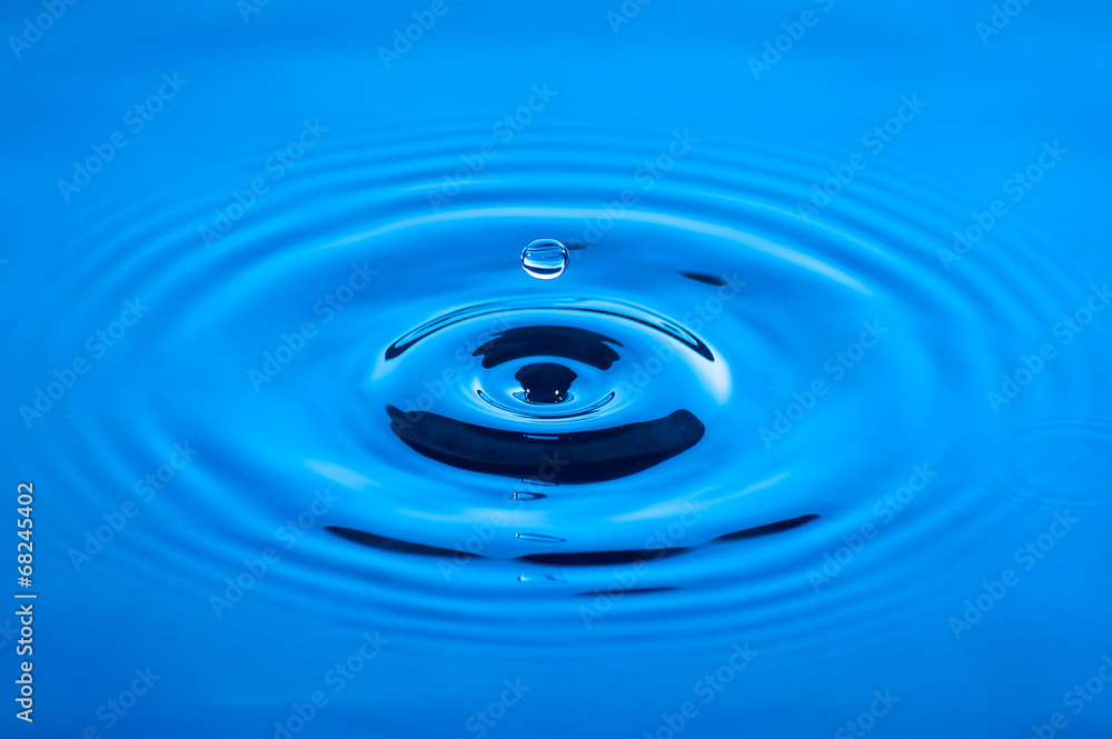 Waves of water caused by the falling droplets with blue lighting Waves of water caused by the falling droplets with blue lighting