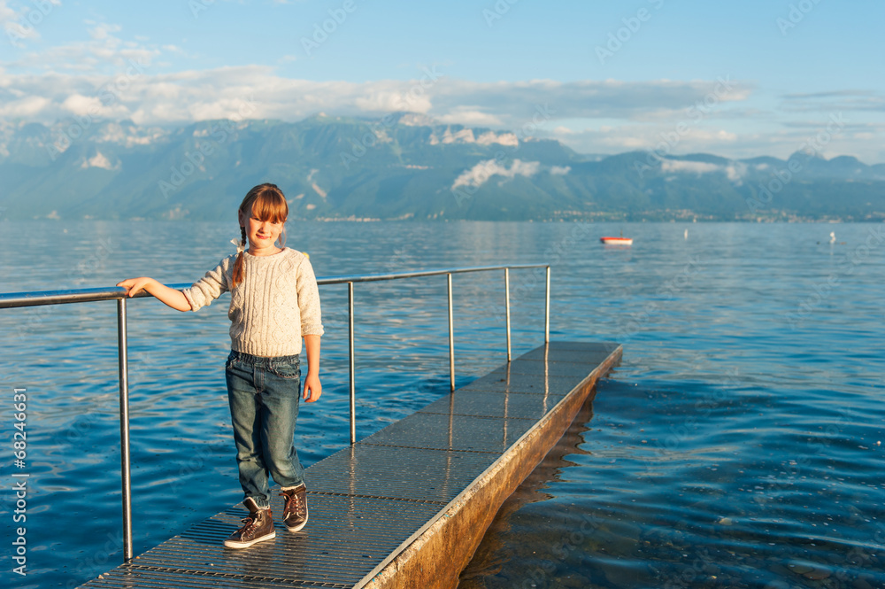 Sunset portrait of a cute little girl next to beautiful lake