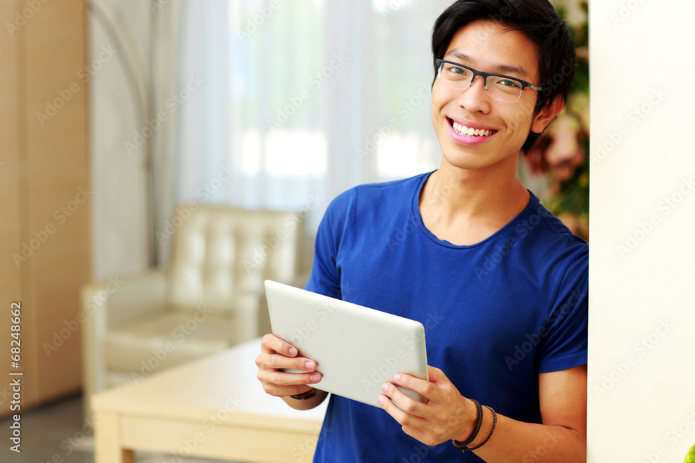 Fototapeta premium Happy young asian man standing with tablet computer at home