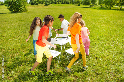 Фотография Kids run around playing musical chairs game