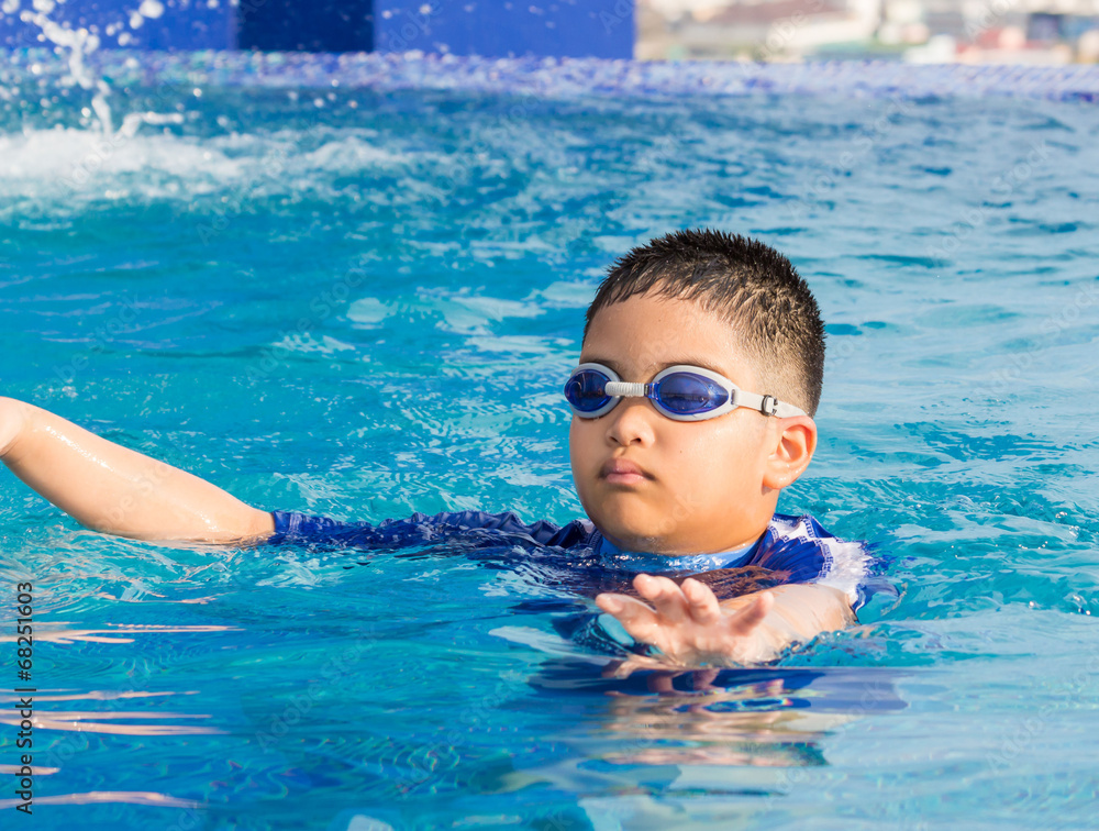 Cute little boy with his goggles on in swimming pool